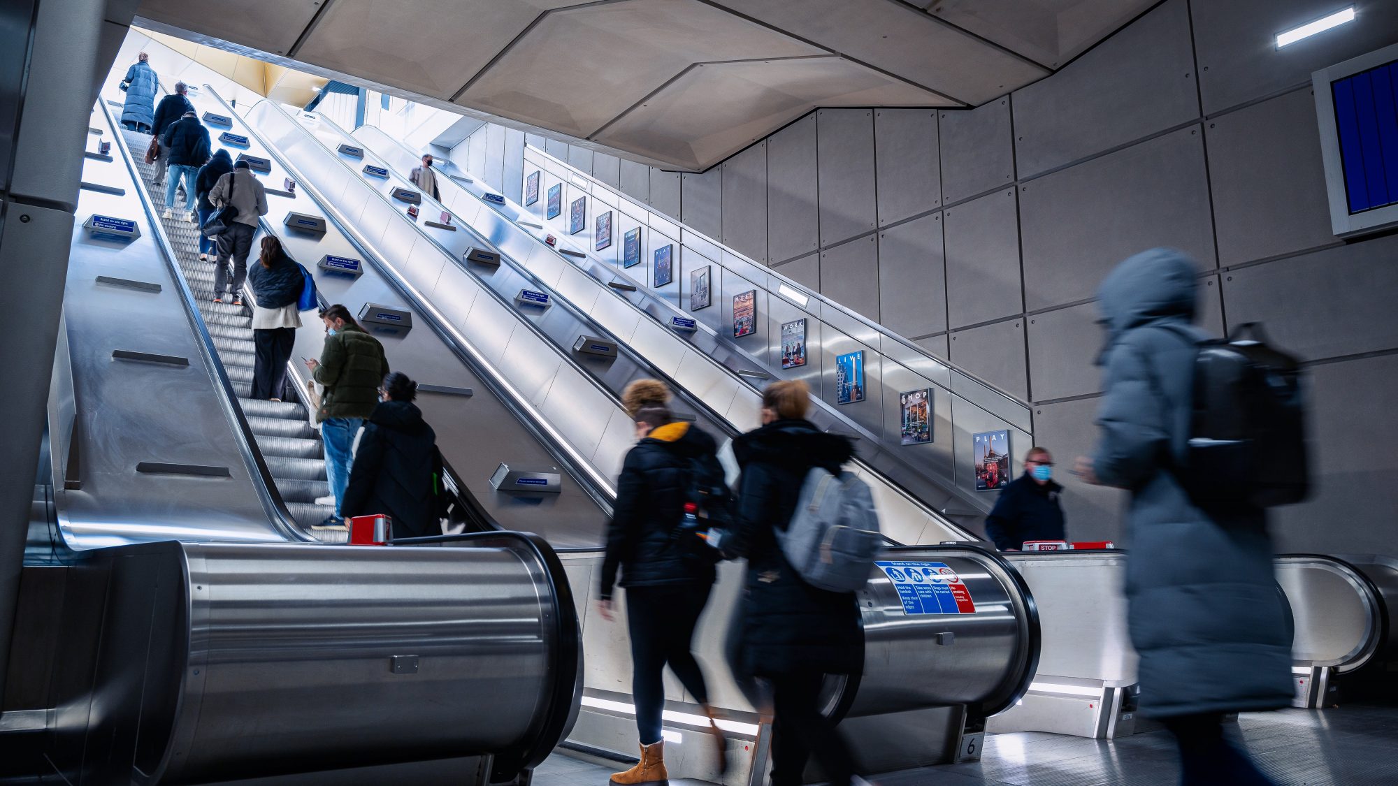 People walking up an escalator as they leave the London Underground station.