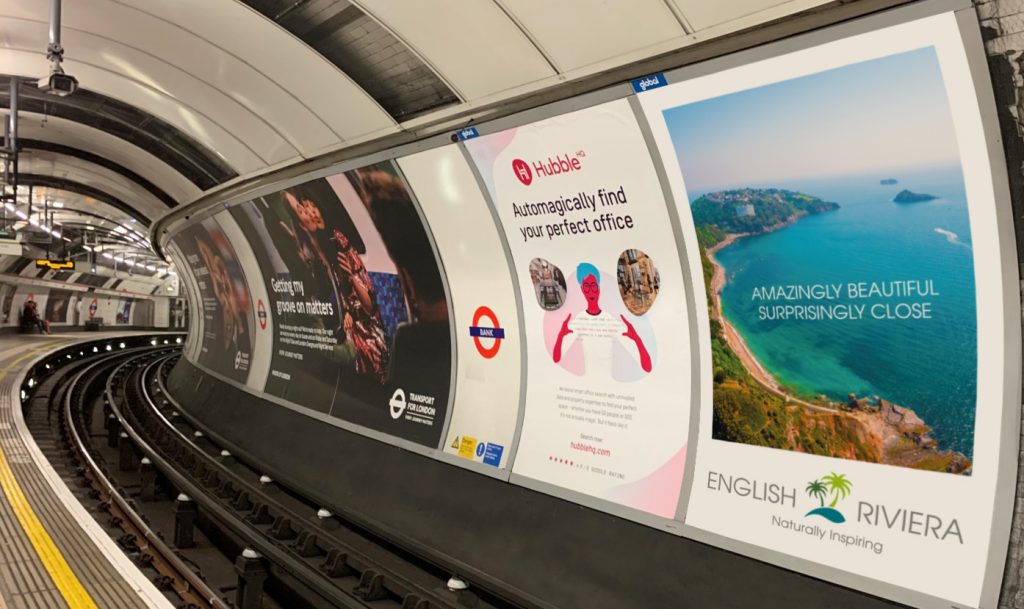 The platform of the London Underground station with 16-sheet adverts across the track.